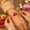 ACCESSHER Gold Plated Maroon Beads & Pearl Rakhi - Set with Roli, Kumkum & Raksha Bandhan Greeting Card